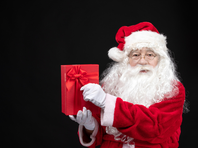 Санта Клаус с подарком в руках на черном фоне