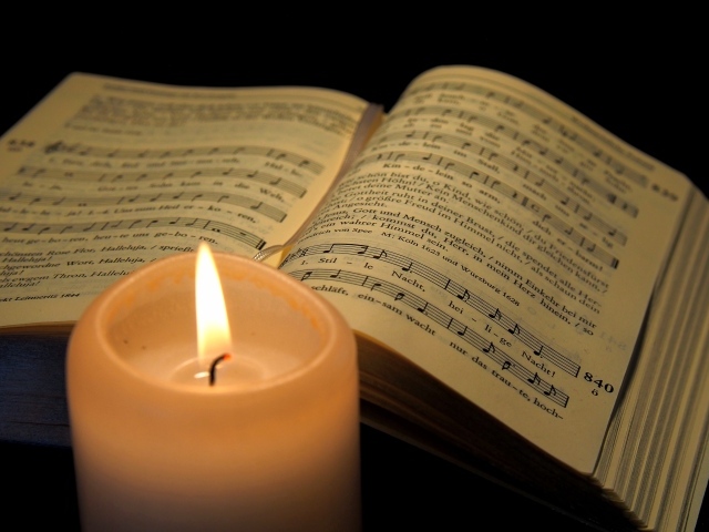 Зажженная свеча с книгой с нотами