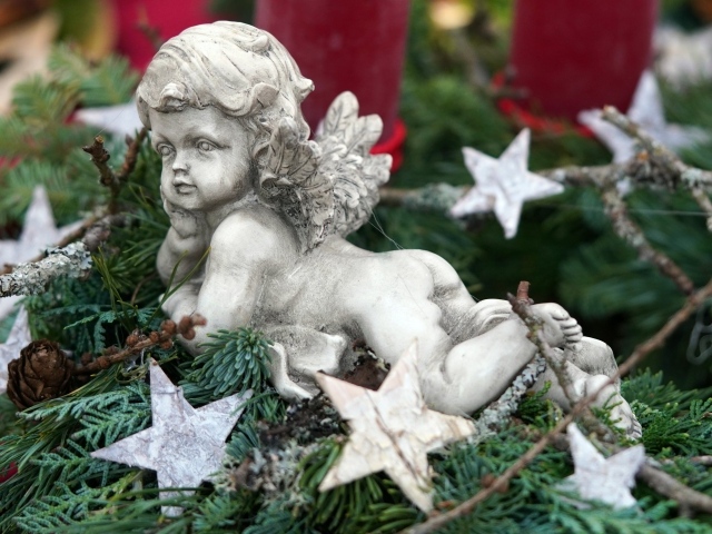 Статуэтка ангел лежит на ветках туи