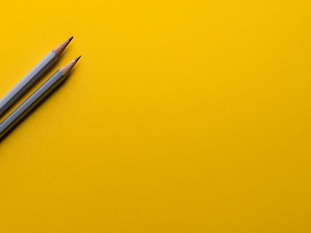 Два карандаша на желтом фоне
