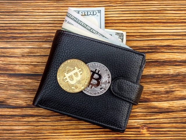Черный кожаный кошелек с долларами и монетами биткоин
