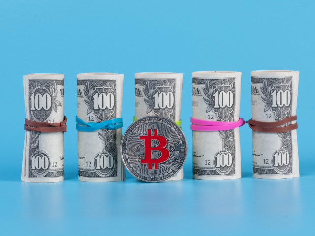 Доллары с монетой биткоин на голубом фоне