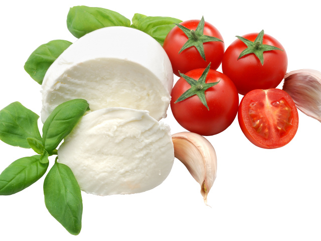 Сыр на белом фоне с помидорами, листьями базилика и чесноком
