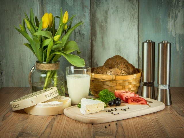 Сыр с овощами на столе с хлебом и букетом тюльпанов