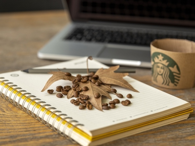 Зерна кофе с листом и блокнотом на столе