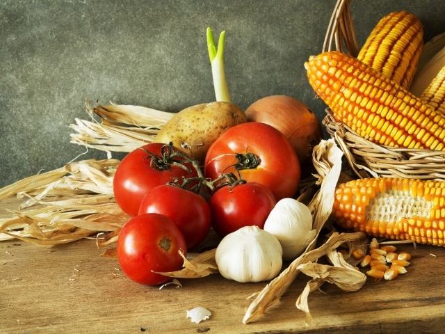 Кукуруза, чеснок и помидоры на столе