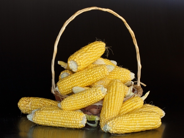 Кукуруза в корзине на черном фоне