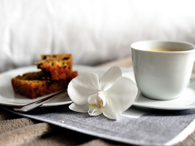 Чашка кофе с цветком орхидеи и куском кекса