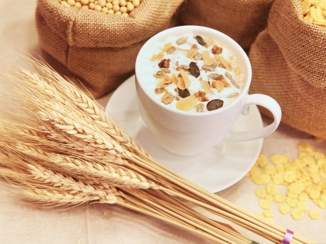 Чашка молока с хлопьями на столе с пшеницей