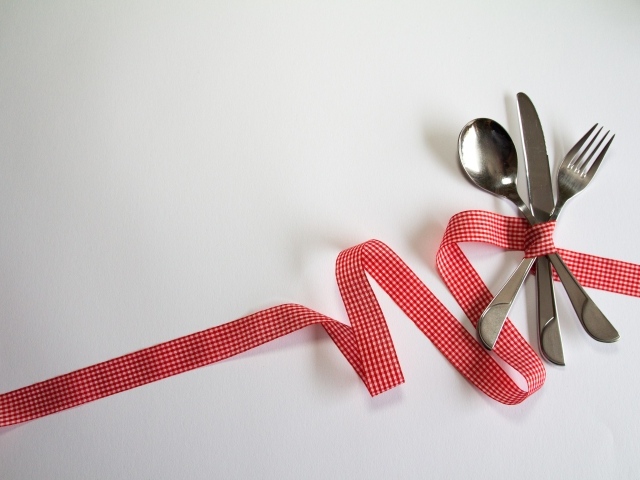 Столовые приборы перевязаны лентой на сером фоне