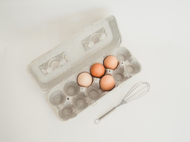 Четыре яйца в лотке на сером фоне