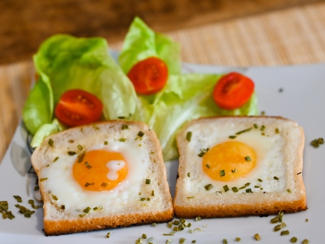 Яичница с хлебом, помидорами и листьями салата на завтрак