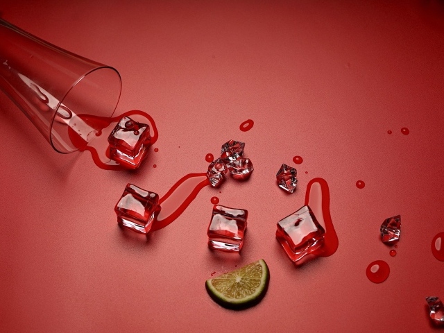 Кубики льда на красном фоне с кусочком лайма и стаканом
