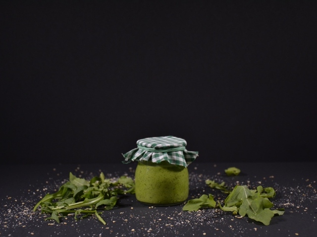 Банка соуса песто на черном фоне