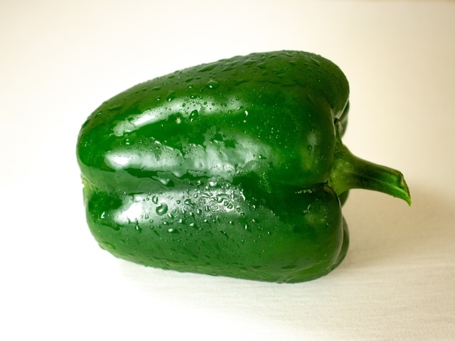 Крупный зеленый перец на белом фоне