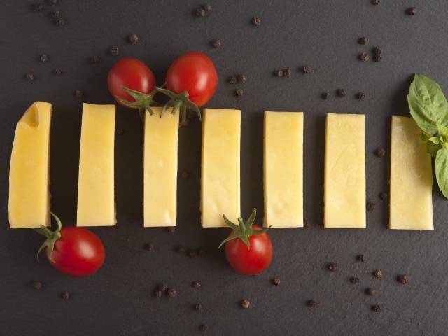 Кусочки сыра с помидорами на сером столе