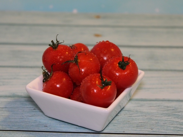 Красные мокрые помидоры в белой тарелке