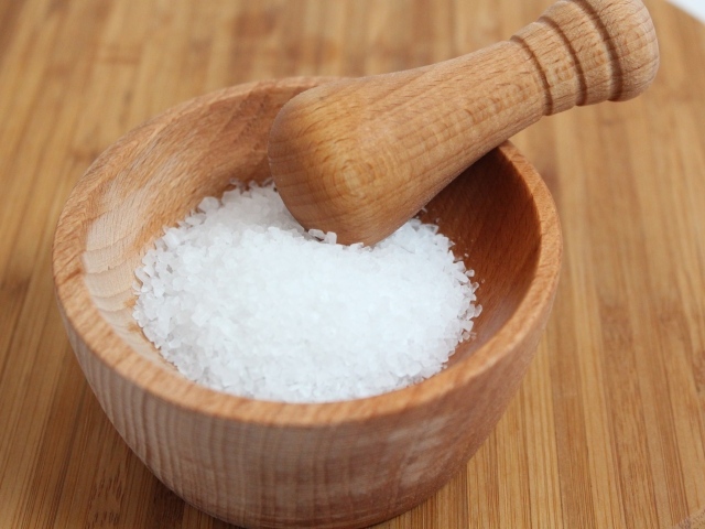 Соль в деревянной ступке на столе 