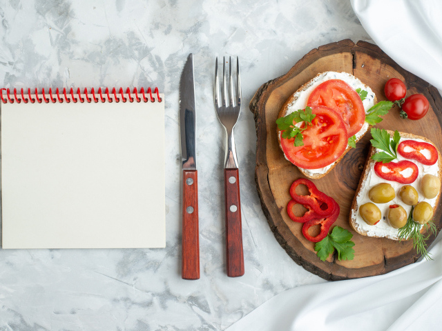 Бутерброды на столе со столовыми приборами и блокнотом