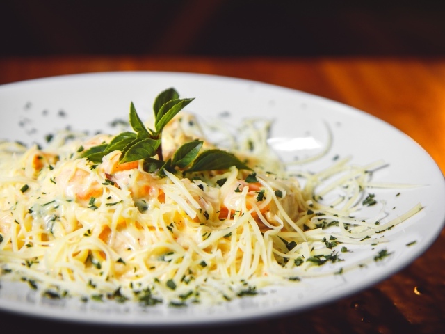 Спагетти с сыром и помидорами на белой тарелке