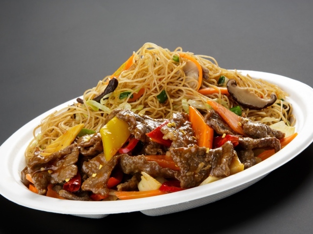 Острая лапша с грибами на белой тарелке на сером фоне