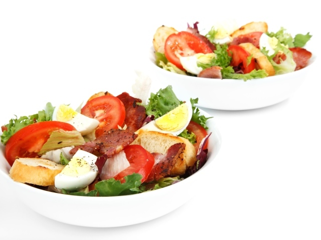 Две миски вкусного салата на белом фоне