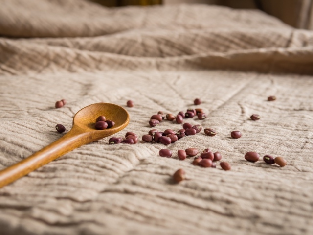 Деревянная ложка на скатерти с фасолью 