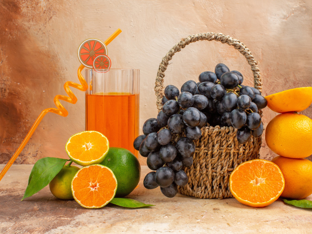 Корзина с виноградом на столе с апельсинами и лаймом