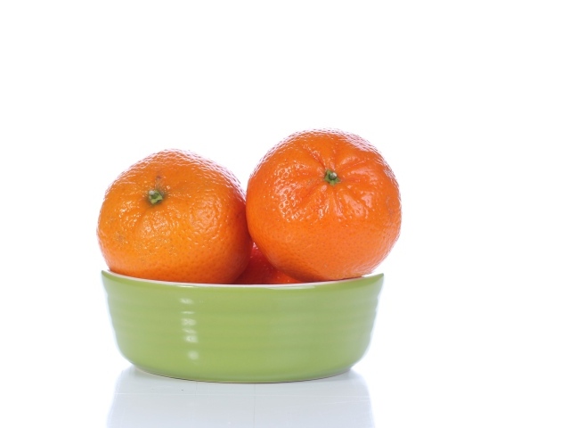 Красивые мандарины в миске на белом фоне