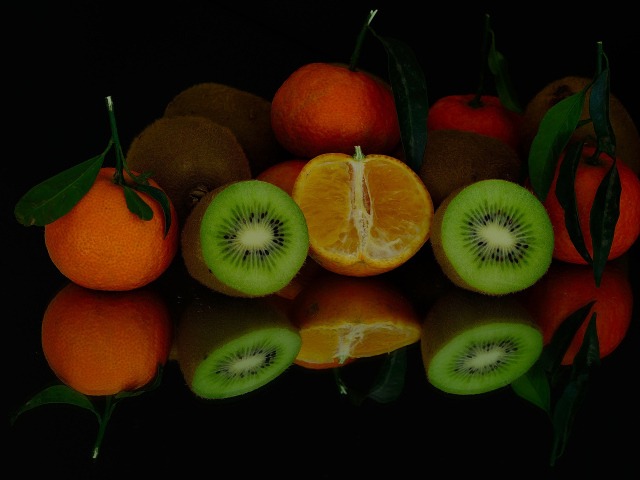 Цитрусовые фрукты на черной зеркальной поверхности