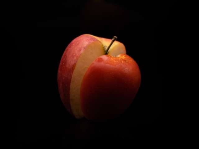 Разрезанное красное яблоко на черном фоне