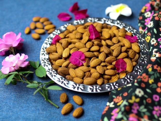 Вкусные миндальные орехи на тарелке с цветами