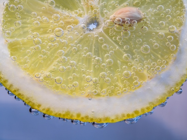 Кружок лимона в каплях воды на голубом фоне