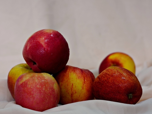 Много красных яблок с белой тканью 