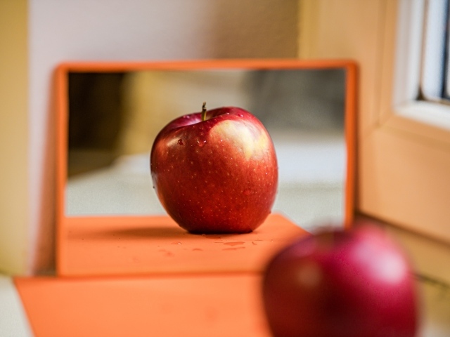 Больше красное яблоко отражается в зеркале 
