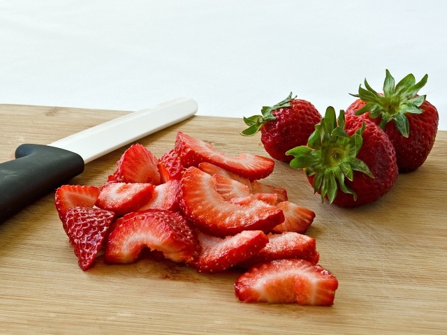 Красная клубника нарезана на деревянной доске