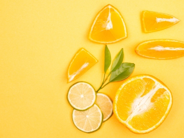 Нарезанные плоды апельсина и лайма на желтом фоне
