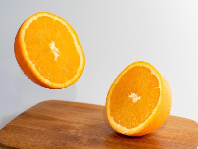 Две половинки апельсина на деревянной доске