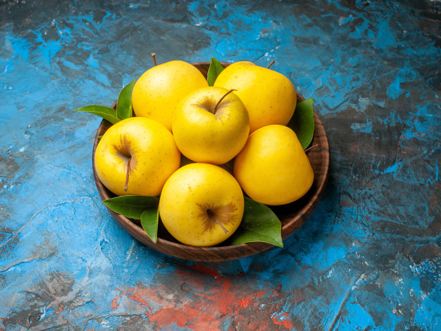 Деревянная тарелка с яблоками на столе