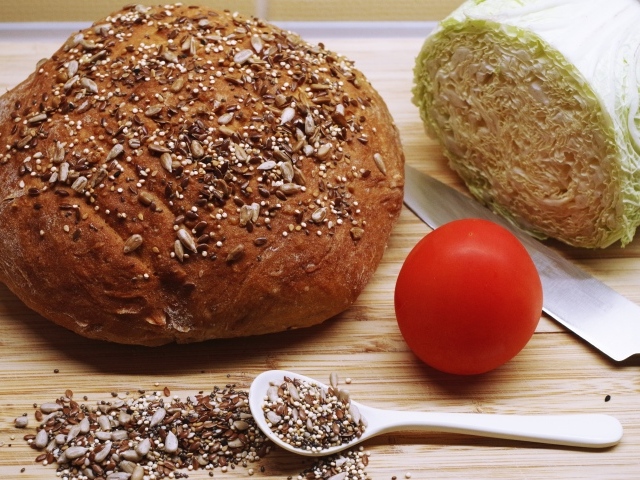 Буханка хлеба на столе с капустой и помидором