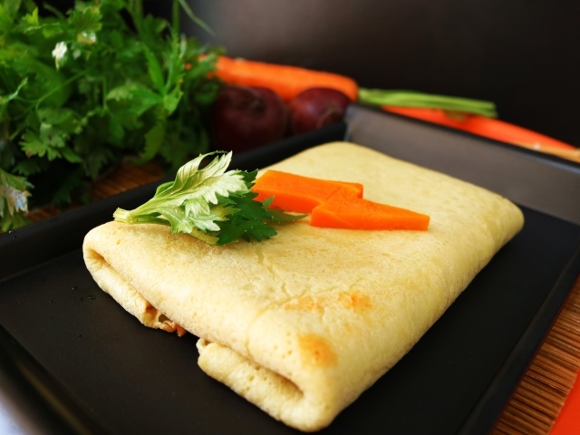 Блинчик на тарелке с морковью и веточками петрушки