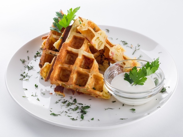 Вафли с соусом и зеленью на тарелке