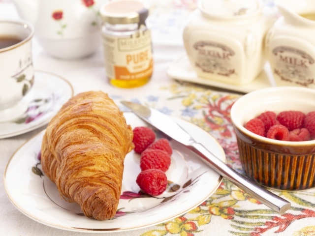 Круассан с ягодами малины на тарелке