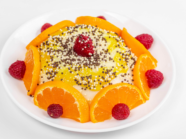 Десерт с кусочками апельсина и ягодами малины на белом фоне