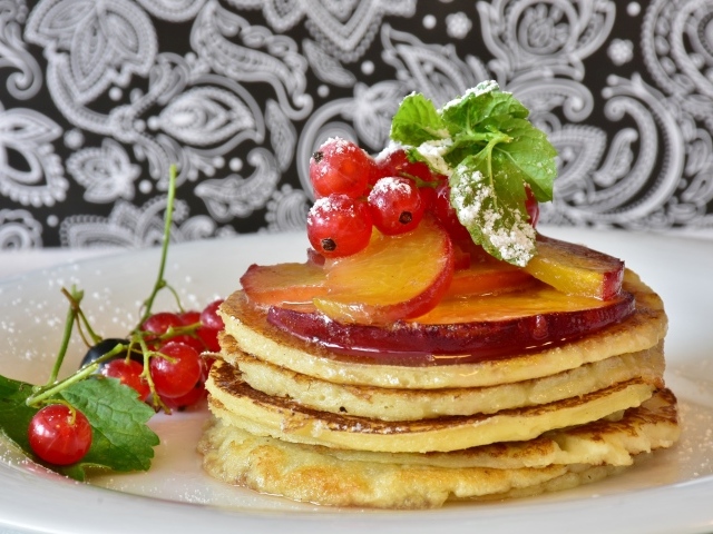 Оладьи на тарелке с ягодами смородины  и сливы