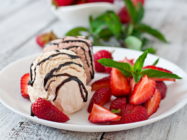 Шарики мороженого на тарелке с кусочками клубники