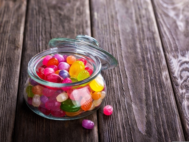 Разноцветные конфеты в стеклянной банке на столе