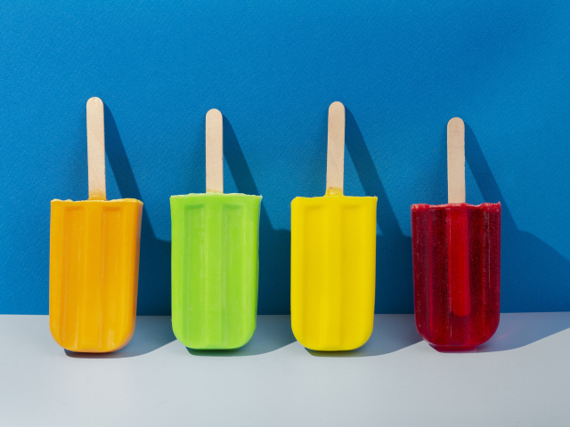 Разноцветное фруктовое мороженое на фоне голубой стены