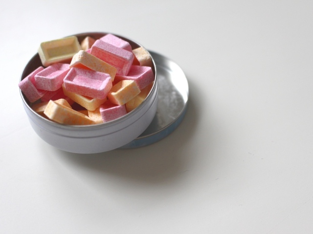 Розовые и оранжевые конфеты в коробке на сером фоне