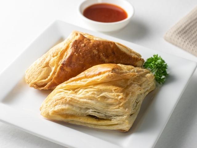 Слоеная выпечка на белой тарелке с соусом